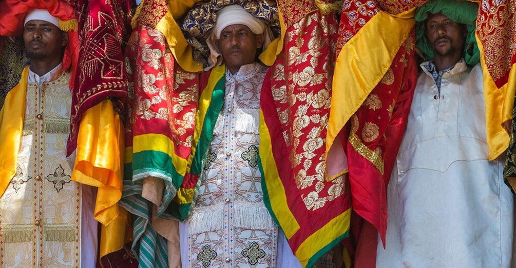 A group of men in traditional ceremonial attire with elaborate patterns and vibrant colors. 2
