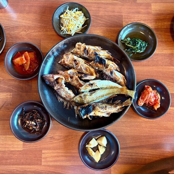 A plate of fried fish surrounded by various dipping sauces and side dishes. 5