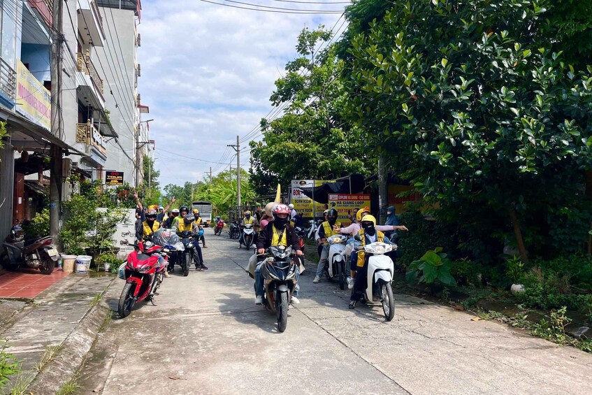 A group of motorcyclists on a street, some wearing helmets and reflective vests. 2