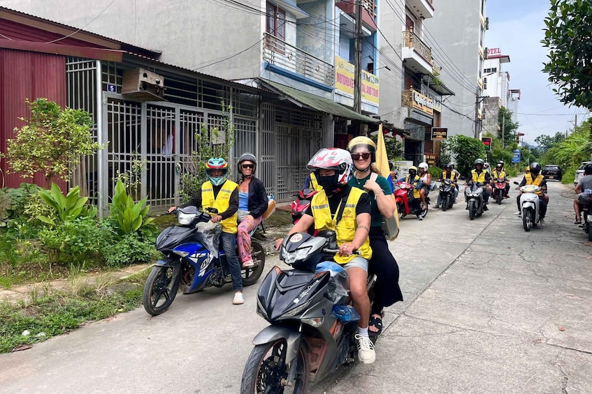 A group of motorcyclists on a street with buildings and a hotel in the background. 5