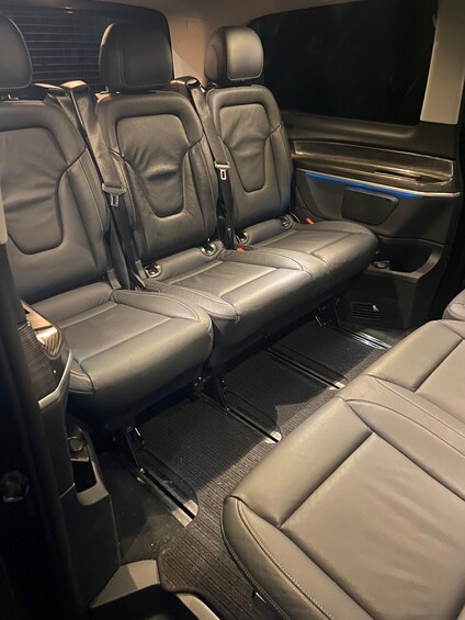 A vehicle interior with black leather seats, a center console, and a rearview mirror. 3
