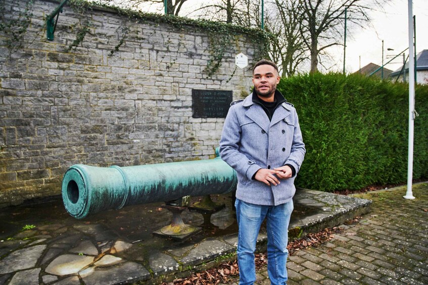 A man standing next to a cannon in a historical setting. 1