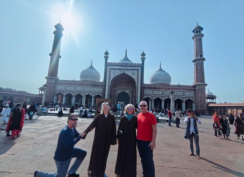 A large mosque with domes and minarets, people walking around, and a clear sky. 4