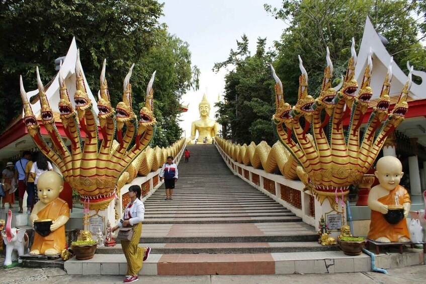 Ein Tempelportal mit goldenen Statuen und einer großen Buddha-Statue im Hintergrund. 1