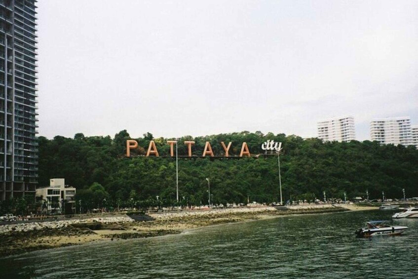 Ein Ufer mit dem Schild 'PATTAYA city' und Gebäuden im Hintergrund. 3