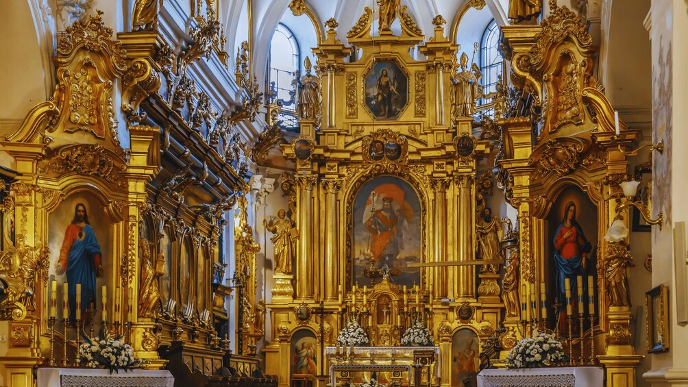 An ornate church interior with golden decorations, statues, and religious paintings. 3