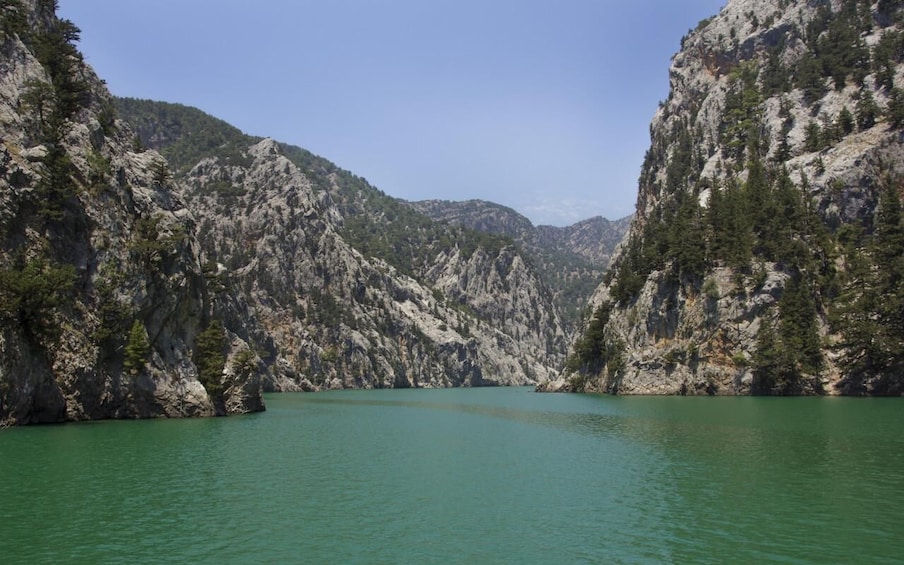 A lake surrounded by rocky mountains with sparse trees. 2