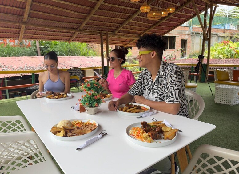 Three people dining at an outdoor table with various dishes. 5