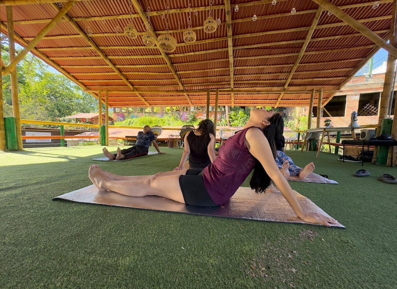 People practicing yoga on mats under a covered area with a bamboo structure. 1