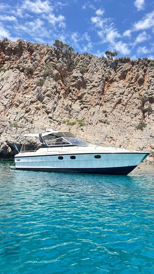 A boat anchored near rocky cliffs with clear blue water. 1
