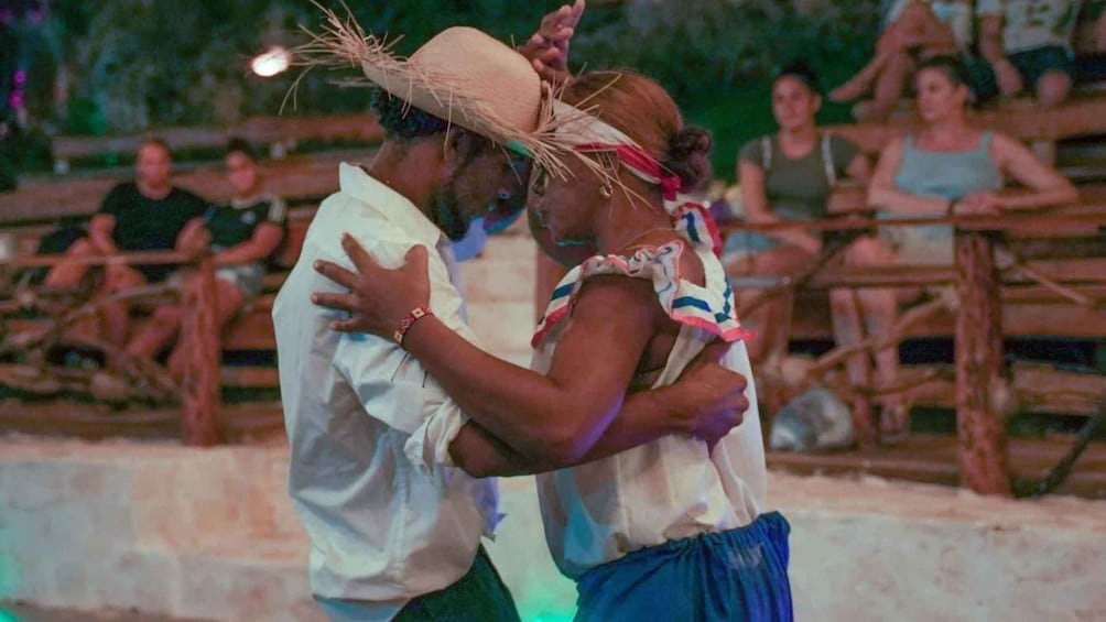 A couple dancing on a stage with an audience in the background. 2
