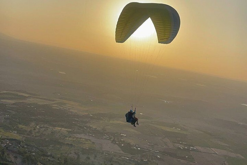 A person paragliding over a landscape with fields and a clear sky. 3