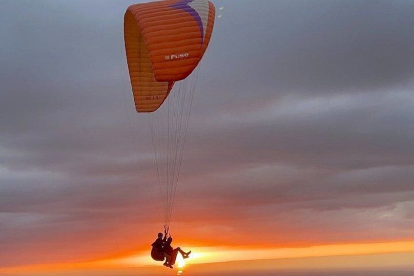 A person skydiving with a parachute labeled 'Fuse' against a sunset sky. 4