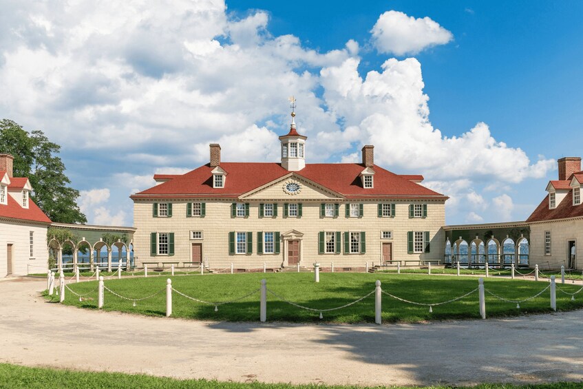 A large historic building with a red roof, green shutters, and a central tower. 5