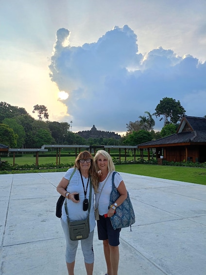 Two people standing in a courtyard with a temple in the background. 2