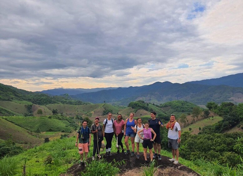 A group of people standing on a hill with a mountainous landscape in the background. 1