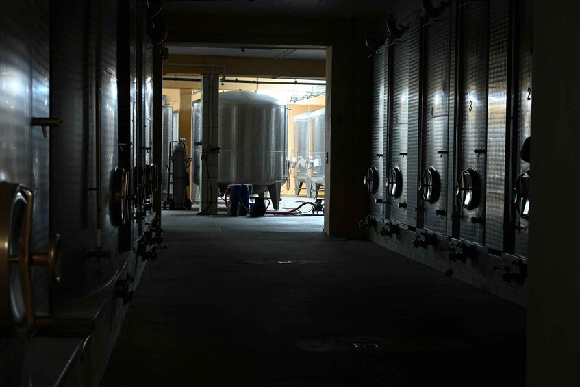A dimly lit industrial facility with large cylindrical tanks and rows of ventilation hoods. 2