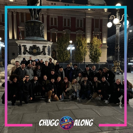 A group of people posing in front of a historical fountain with classical architecture, surrounded by buildings and street lamps. 2