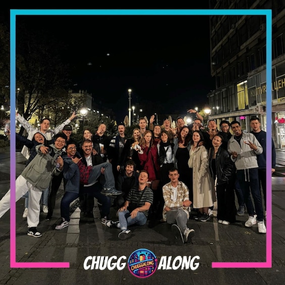A group of people posing for a photo on a city street at night. 1