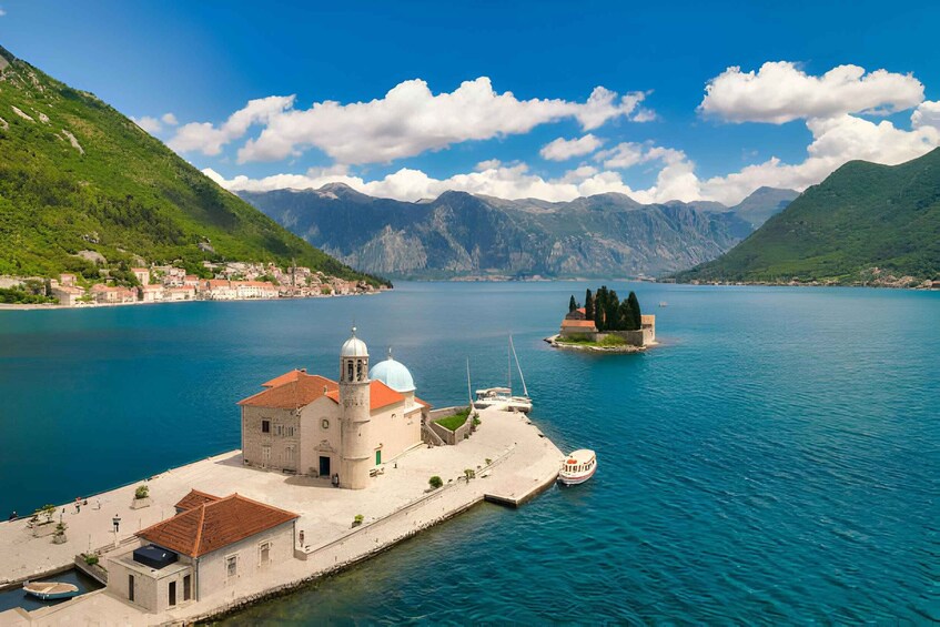 A coastal town with a prominent church, a small island, and mountains in the background. 2
