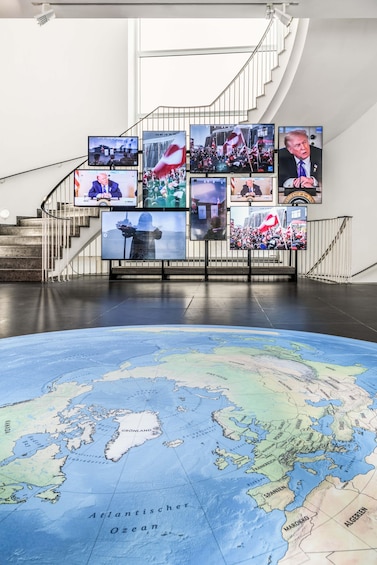 A large globe with a staircase and multiple screens displaying various scenes. 2