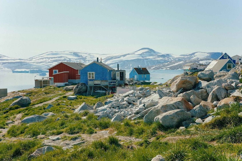 A coastal village with colorful houses, a rocky shoreline, and snow-capped mountains in the background. 5