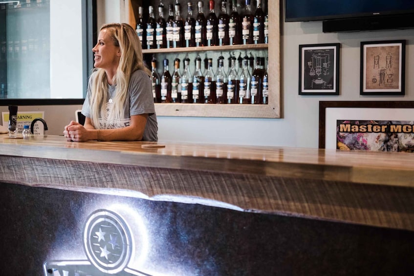 A person sitting at a bar counter with a wine rack in the background. 2