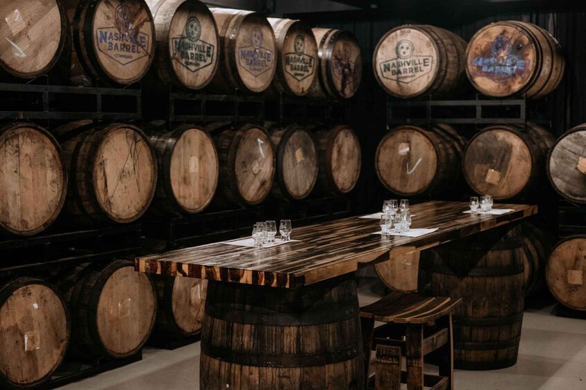 A bar with wooden barrels stacked behind it and a long wooden bar in the foreground. 4