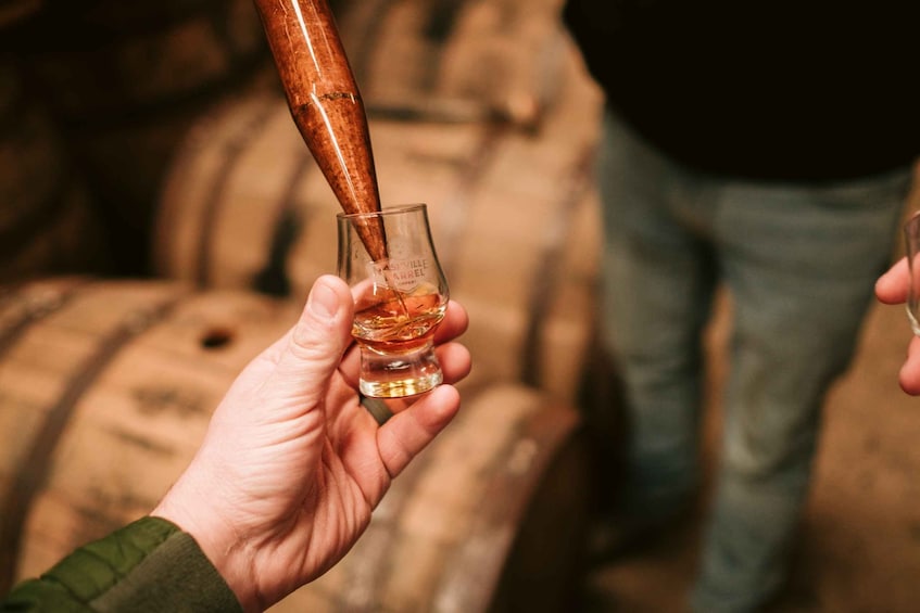 A person pouring whiskey into a small glass. 5