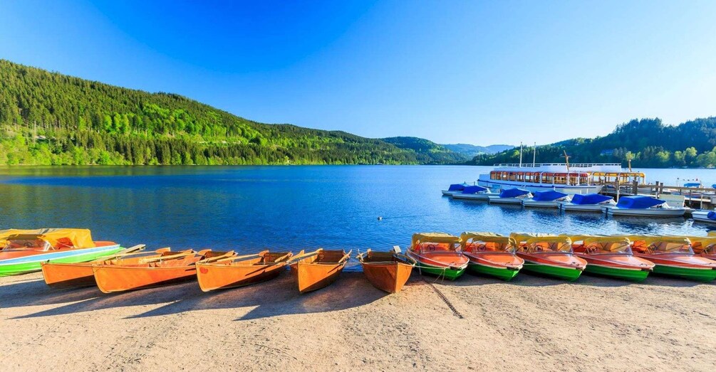 A lake with boats on the shore and a larger boat docked at the pier. 2