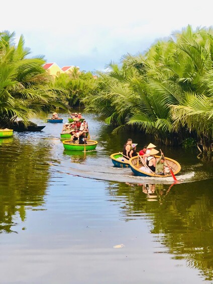 People paddling in small boats along a waterway surrounded by palm trees. 2