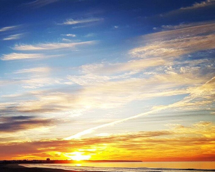 A sunset over a beach with a clear sky and clouds. 2