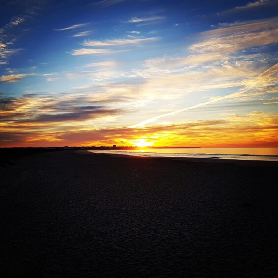 A beach at sunset with the sun setting over the horizon. 4