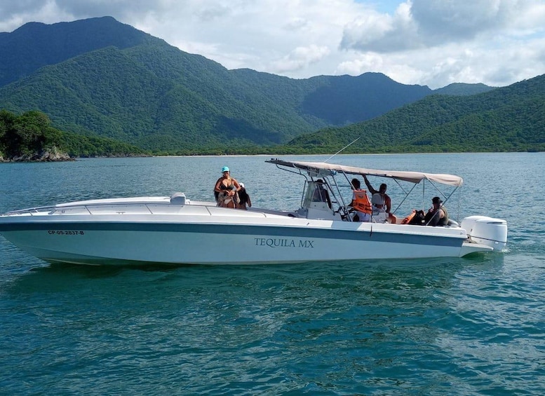 A speedboat named 'TEQUILA MX' on a calm lake with lush green mountains in the background. 2
