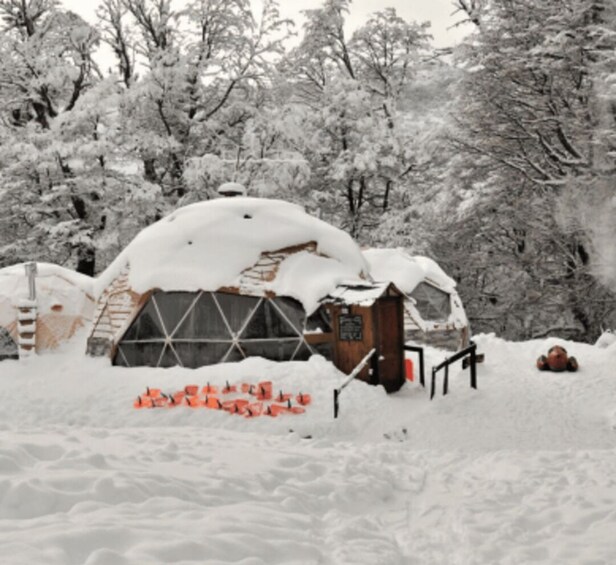 A snow-covered igloo-like structure with a wooden door and a snow-covered roof. 2