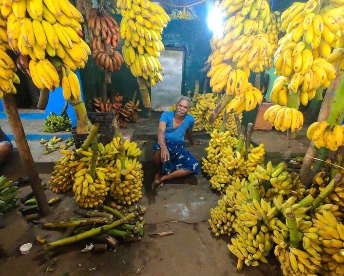 A person surrounded by large bunches of bananas in a market setting. 1