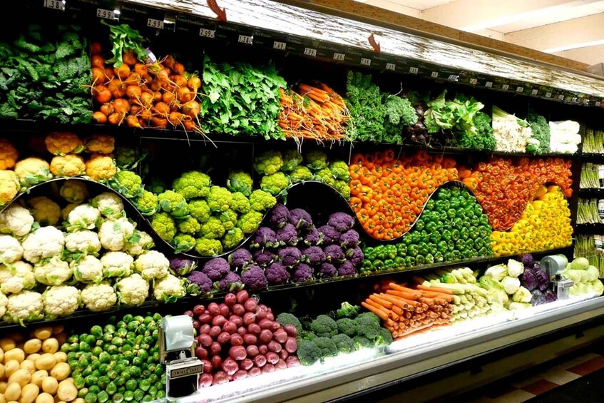 A grocery store's produce section with various vegetables like cauliflower, broccoli, and carrots. 4