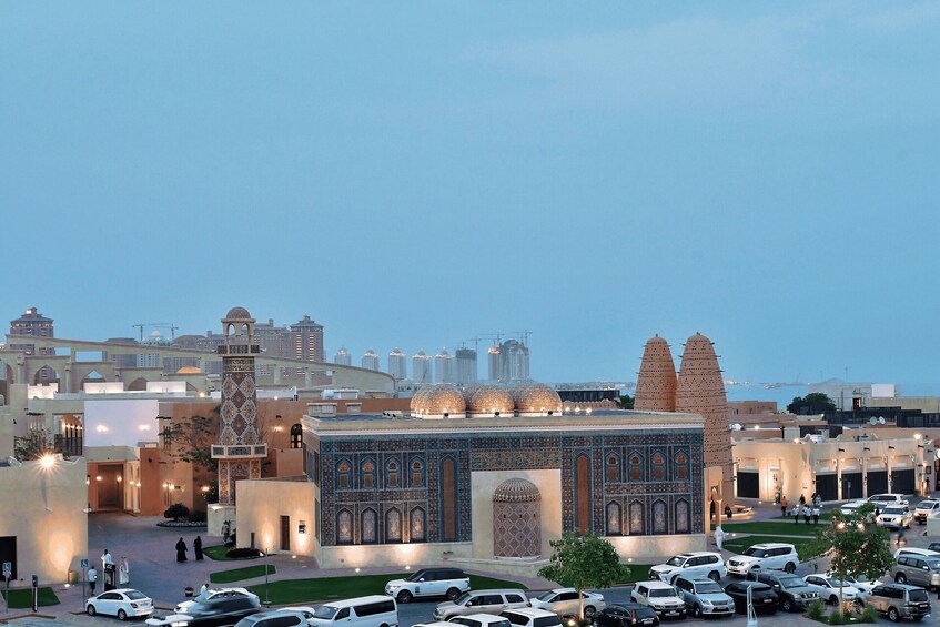 A mosque with intricate tile work and minarets, surrounded by modern buildings and parked cars. 3
