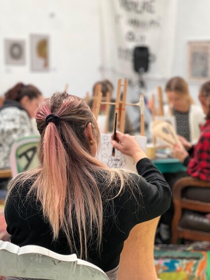 A person with a ponytail painting on a canvas. 2