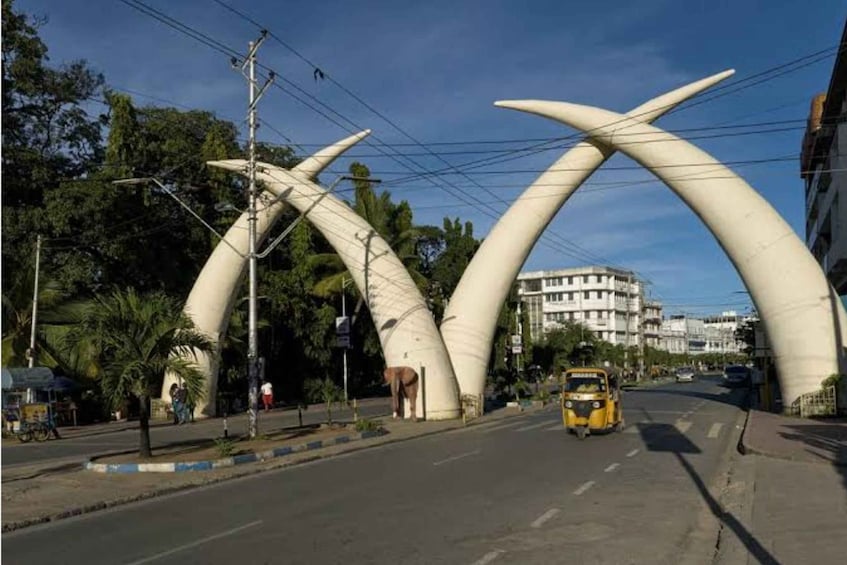 A street with a unique archway structure, a yellow taxi, and buildings in the background. 1