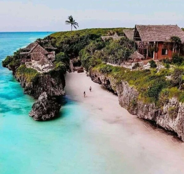 A coastal village with thatched-roof houses, a narrow beach, and clear turquoise waters. 3