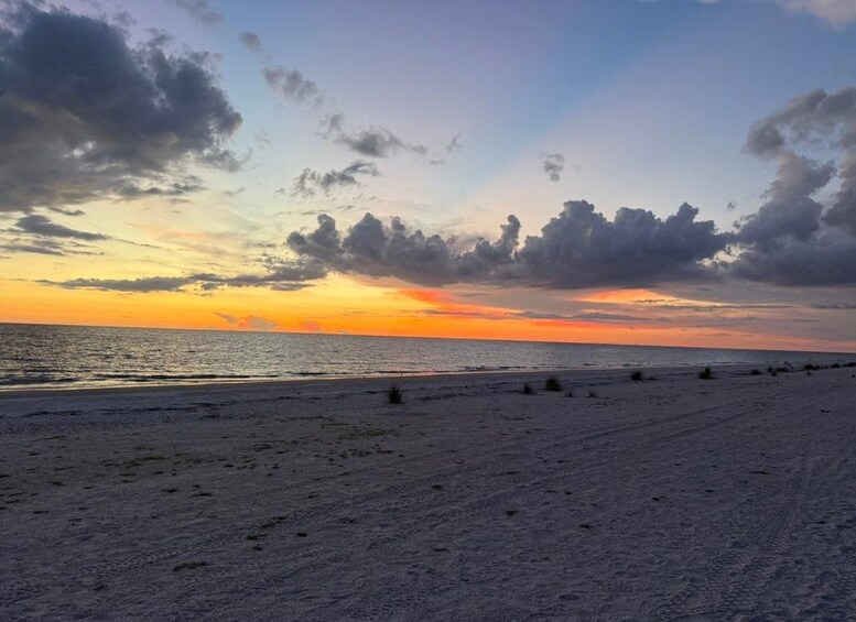 A beach at sunset with clouds in the sky and the ocean in the background. 5