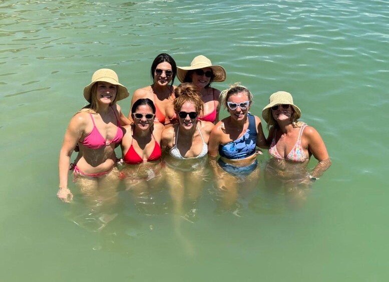 A group of people in a shallow body of water wearing hats and swimsuits. 3