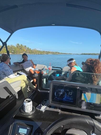 A boat interior with a Garmin navigation screen, a cup holder with a drink, and a can of beer. 2