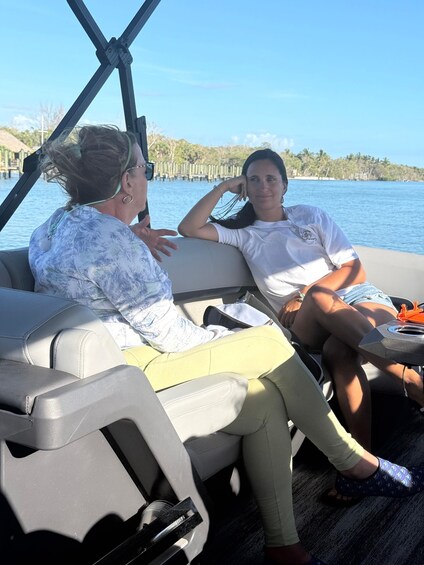 Two people on a boat with a water body and a wooden dock in the background. 4