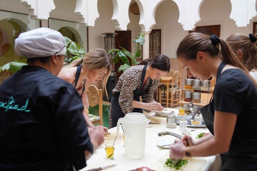 A group of people preparing food in a courtyard with arches and plants. 5
