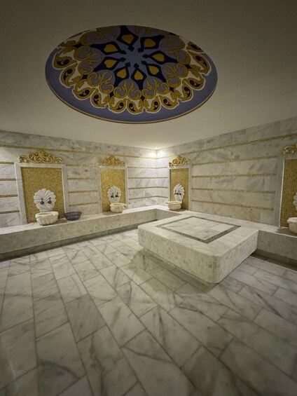 A luxurious bathroom with marble floors, ornate wall decorations, and a central circular design on the ceiling. 1