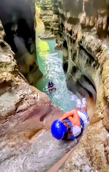 A person in a blue helmet and white shorts climbing a rocky cliff. 3