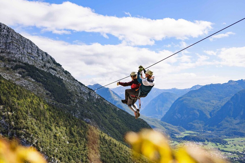 A person bungee jumping from a bridge over a valley with mountains in the background. 1