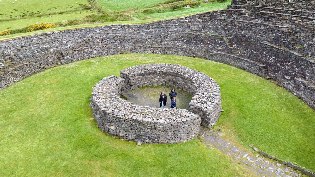 A stone amphitheater with a circular stage surrounded by grass. 1